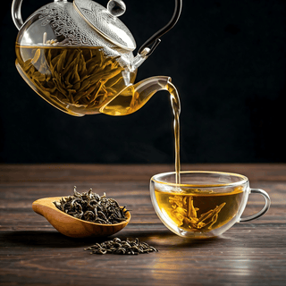 Tea being poured from a glass teapot into a glass cup on a wooden surface.